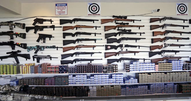 Rifles and ammunition line a wall at a gun shop. [AP Photo/Elaine Thompson, File]