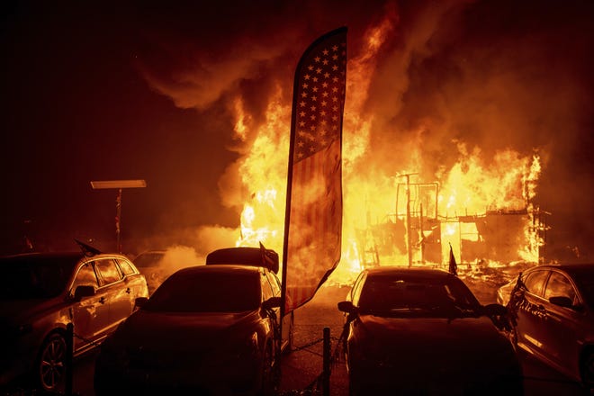 Flames consume a car dealership as the Camp Fire tears through Paradise, Calif., on Thursday, Nov. 8, 2018. Tens of thousands of people fled a fast-moving wildfire Thursday in Northern California, some clutching babies and pets as they abandoned vehicles and struck out on foot ahead of the flames that forced the evacuation of an entire town and destroyed hundreds of structures. (AP Photo/Noah Berger)