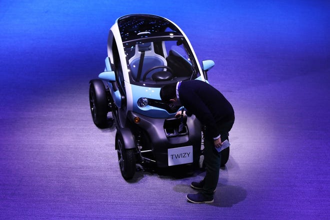 An attendee inspects a Renault Twizy compact electric automobile on the first day of the 87th Geneva International Motor Show in Geneva in March 2017. [Bloomberg, file / Chris Ratcliffe]