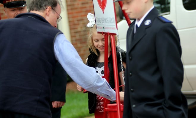 Roxy Hudson watches as Chris Mabry puts money in a kettle at the kick off for the Salvation Army bell-ringing season on Thursday. [Brittany Randolph/The Star]