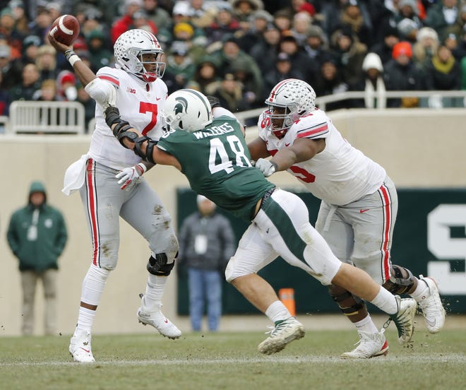 Ohio State Buckeyes quarterback Dwayne Haskins Jr. (7) gets hit by Michigan State Spartans defensive end Kenny Willekes (48) as the releases the ball over offensive lineman Thayer Munford (75) during the third quarter of the NCAA football game at Spartan Stadium in East Lansing, Mich. on Nov. 10, 2018. Ohio State won 26-6. [Adam Cairns/Dispatch]