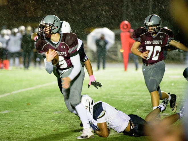 Westford Academy runner Cam Faretra drags a Lawrence defender in the rain Nov. 9. The Grey Ghosts won, 32-6. [Courtesy photo/Ann Antes]