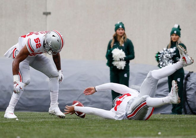 Ohio State Buckeyes long snapper Liam McCullough (49) and linebacker Dante Booker Jr. (52) pin a punt from Ohio State punter Drue Chrisman, not pictured, at Michigan State's 5-yard line during the third quarter of the game against Michigan State on Saturday at Spartan Stadium in East Lansing, Michigan. [Photo by Joshua A. Bickel]