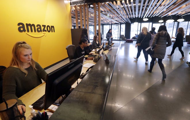 Employees walk through a lobby at Amazon's headquarters in Seattle on Tuesday. Amazon, which is growing too big for its hometown, is spreading out to the East Coast. The online shopping giant ended its 14-month-long competition for a second headquarters Tuesday by selecting New York and Arlington, Va., as the joint winners. [Elaine Thompson/The Associated Press]