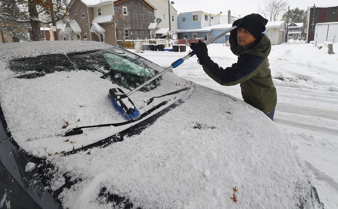 Duryo Gurung of Erie clears snow from his car on Hickory Street in Erie on Nov. 10. [JACK HANRAHAN/ERIE TIMES-NEWS]