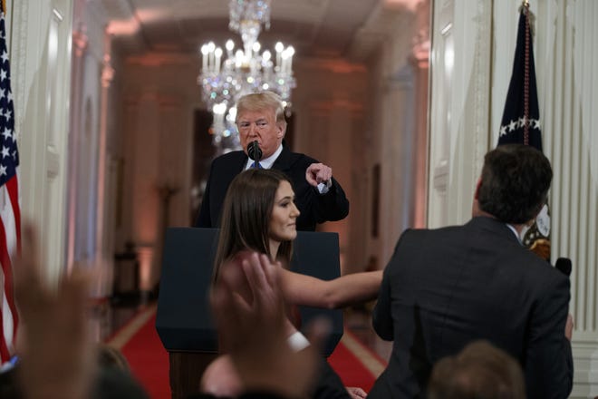 President Donald Trump watches as a White House aide reaches to take away a microphone from CNN journalist Jim Acosta during a news conference on Nov. 7 in the East Room of the White House in Washington. [AP Photo/Evan Vucci, File]