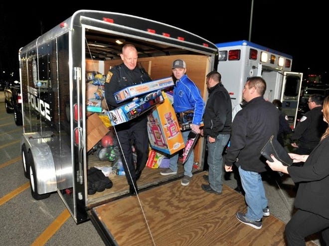 John Hurley, of the Braintree Police Department, helps unload toys from the back of a police trailer during the Braintree Christmas Party on Thursday, Dec. 7, 2017. [Tom Gorman/ The Patriot Ledger]