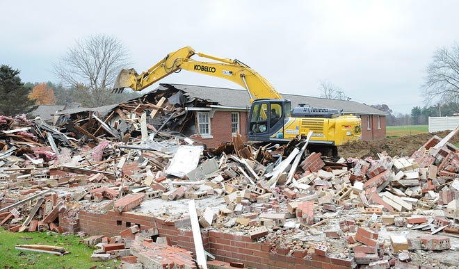 Several of the last standing original buildings of the former State Hospital north of Cambridge are being razed. Workers using trackhoes were doing the demolition work Tuesday. An enclosed brick hallway between buildings also were brought down.