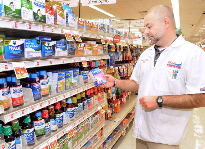Cambridge Riesbeck's Pharmacist Darren Wooley holds one of the most popular over-the-counter medications for combating the flu - Theraflu. Riesbeck's shelves are loaded with a variety of flu, cold, sore throat medicines.