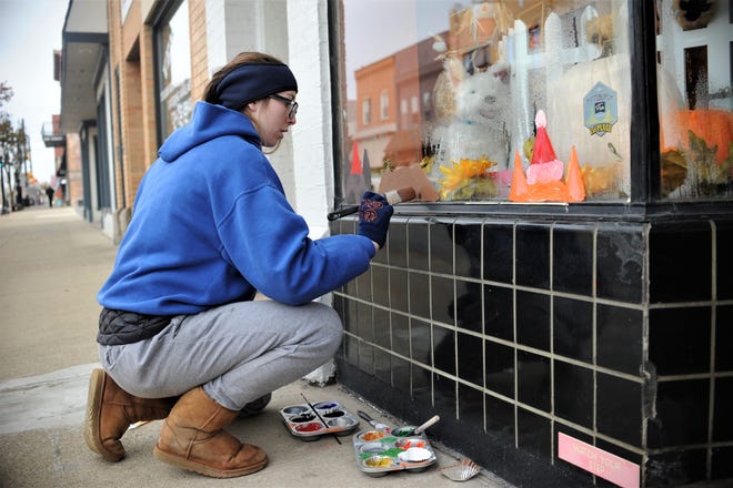 Lincoln High School junior Avery Dudek, 17, paints a dog on the window of Grand Paws Pet Salon on Wednesday afternoon at Lawrence Avenue in Ellwood City. [Dani Fitzgerald/ECL Staff]