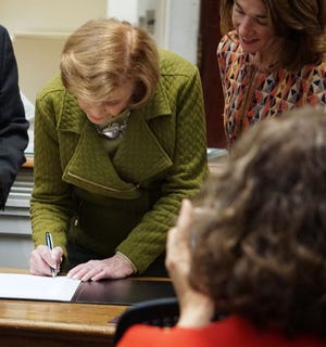State Sen. Harriette Chandler, with Lt. Gov. Karyn Polito looking on, takes part in a ceremonial signing of the state's new civic education bill in Worcester at the American Antiquarian Society in Worcester.