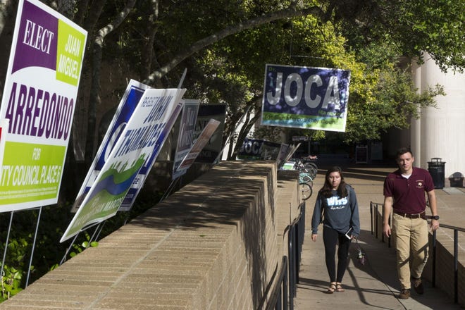 Students walk past campaign signs during early voting at Texas State University earlier this month. Students will be able to vote early in the Dec. 11 runoff election at locations on campus, but there won't be an on-campus voting spot on election day. [LYNDA M. GONZALEZ/AMERICAN-STATESMAN]