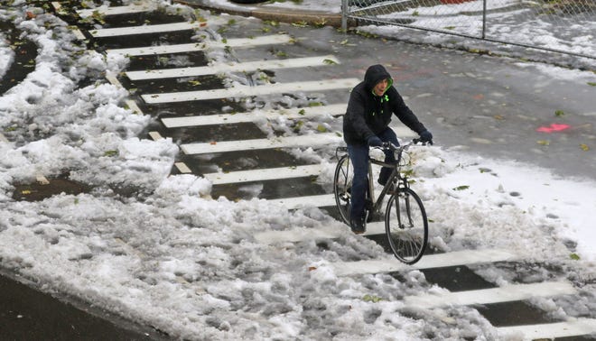 A man on a bike makes his way through the slush along Fountain Street in Providence on Friday . The storm dumped a few inches of snow on the city before turning to rain. [The Providence Journal / Steve Szydlowski]
