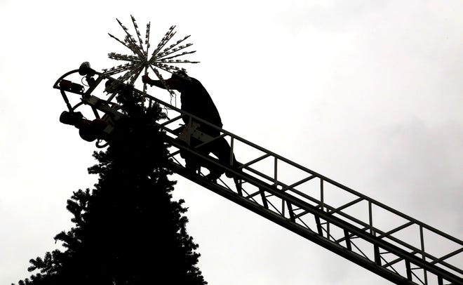 Scott Damas, an Ashland Fire Department firefighter, climbs the ladder to put the star on top of the the 40-feet tall Christmas tree at Corner Park on Saturday. The city will host its inaugural tree lighting ceremony on Dec. 1, following the Christmas Parade in downtown Ashland at 6 p.m.