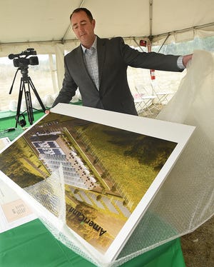 Just before guests and most of the press arrive, AmeriCann CEO Tim Keogh unwraps just-delivered artist's renderings of his planned medical marijuana facility, seen at a groundbreaking for the Massachusetts Medical Cannabis Center, Tuesday, September 25, 2018, in Freetown, Massachusetts. [Herald News File Photo | Jack Foley]