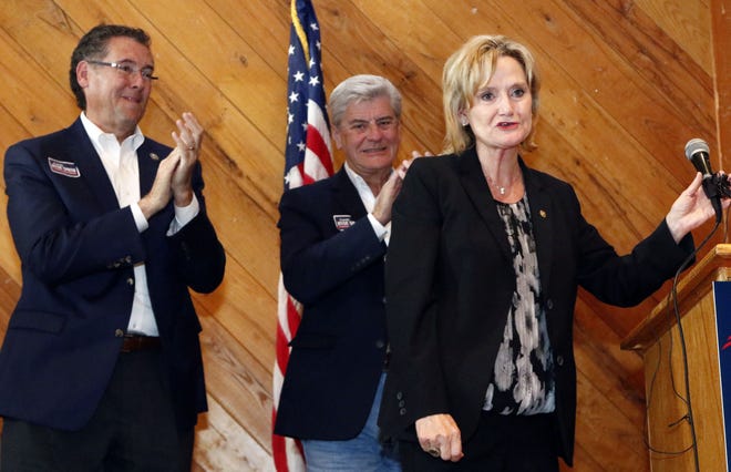 U.S. Rep. Gregg Harper, R-Miss., left, and Gov. Phil Bryant, applaud U.S. Sen. Cindy Hyde-Smith, R-Miss., right, after she spoke to a gathering of supporters in Jackson, Miss., Monday, Nov. 5, 2018. (AP Photo/Rogelio V. Solis)