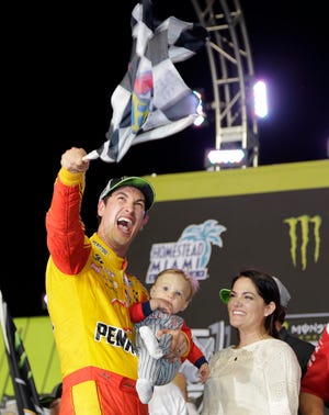 Joey Logano waves a checkered flag as he stands with his wife Brittany Baca and son Hudson after winning NASCAR Cup Series Championship auto race at the Homestead-Miami Speedway, Sunday, Nov. 18, 2018, in Homestead, Fla. (AP Photo/Terry Renna)