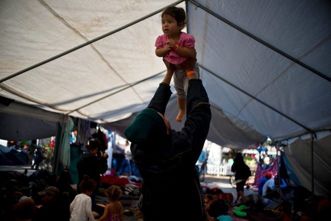 Cesar Elvir, a migrant from Honduras, lifts his daughter Sujhey at a migrant shelter in Tijuana, Mexico, Sunday, Nov. 18, 2018. While many in Tijuana are sympathetic to the plight of Central American migrants and trying to assist, some locals have shouted insults, hurled rocks and even thrown punches at the migrants. (AP Photo/Ramon Espinosa)