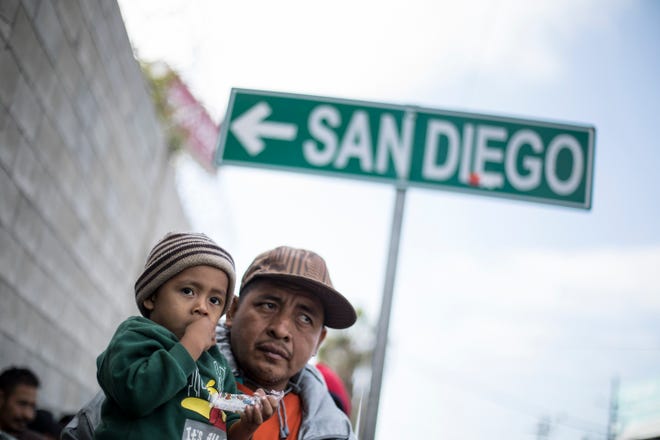 A father and his son await tutorship by immigration lawyers in Tijuana, Mexico, Friday, April 27, 2018. Close to to 200 migrants from Central America, mostly from Honduras, arrived in Tijuana seeking to enter the United States. (AP Photo/Hans-Maximo Musielik)
