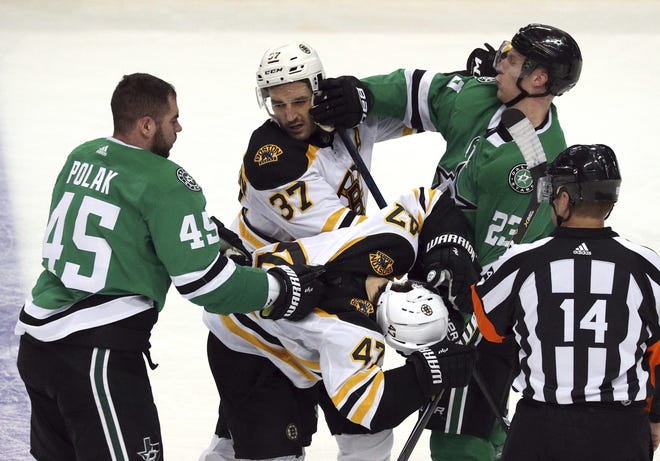 Bruins center Patrice Bergeron (37) and defenseman Torey Krug exchange pushes and shoves with Stars defensemen Roman Polak and Esa Lindell during their game last Friday in Dallas. Bergeron was hurt later in the game. [Richard W. Rodriguez/AP]