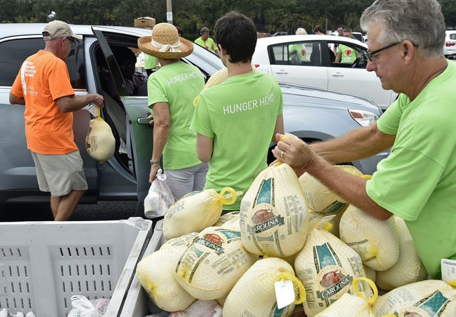 All Faiths Food Bank volunteers, from left, Jeff and Sharon Boss, Domingo Alvarez and Don Wilson hand out Thanksgiving meals on Tuesday in the Robarts Arena parking lot in Sarasota. More than 2,000 turkeys and sides were distributed. [Herald-Tribune staff photo / Thomas Bender]