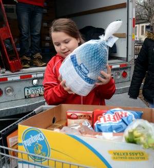 Volunteer Amiliah Kennett, 11, puts a turkey into a cart Tuesday during the annual Friends of Assisi food donation at the Rev. John O'Neill Gymnasium at St. James School in Danielson. [Aaron Flaum/NorwichBulletin.com]