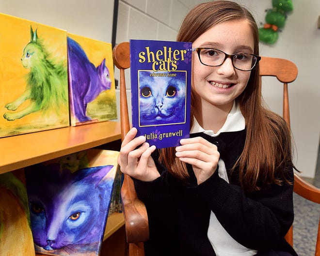 St. Andrew Catholic School fifth-grader Julia Grunwell shows the book she wrote and published, "Shelter Cats: Edwena's Home." [ART GENTILE/PHOTOJOURNALIST]