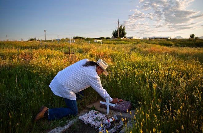 FILE - In this July 14, 2018, file photo, Kenny Still Smoking touches the tombstone of his 7-year-old daughter, Monica, who disappeared from school in 1979 and was found frozen on a mountain, as he visits her grave on the Blackfeet Indian Reservation in Browning, Mont. The number of Indian Country crimes that the U.S. Justice Department decided to prosecute has not shown significant change in recent years, despite programs and attempts to boost both public safety and prosecutions of sexual assaults and other crimes on reservations, according to federal figures Wednesday, Nov. 21, 2018. (AP Photo/David Goldman, File)