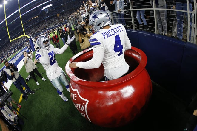 Cowboys quarterback Dak Prescott spends a moment in the Salvation Army kettle after a lift from running back Ezekiel Elliott to celebrate a touchdown against Washington on Thursday. [Ron Jenkins/The Associated Press]