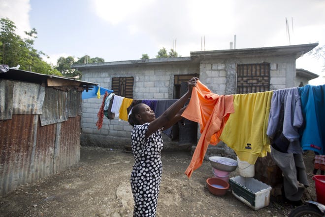 Rose Marie Petit-Frere hangs a shirt to dry at her home in Croix-des-Bouquets, Haiti. The new, three-bedroom home was paid for with money her husband, Jean Felix Petit-Frere, sent home from his job at Butterball. [DIEU NALIO CHERY/FOR THE WASHINGTON POST]