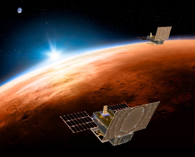 FILE - This illustration made available by NASA in March 2018 shows the twin Mars Cube One project (MarCO) spacecrafts flying over Mars with Earth and the sun in the distance. The MarCOs will be the first CubeSats, a kind of modular, mini-satellite, flown into deep space. They're designed to fly along behind NASA's InSight lander on its cruise to Mars. (NASA/JPL-Caltech via AP)