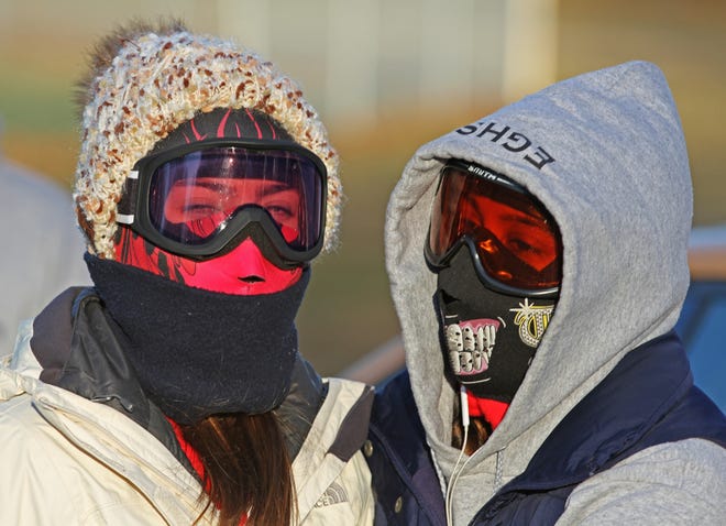 Sonali Shah and Alexis White, both of East Greenwich, bundle up in the 16 degree weather on Thursday to watch the 5th annual Turkey Trot 5K at Warwick City Park. The bitter cold in the region set another record in Providence on Friday. [The Providence Journal / Steve Szydlowski]