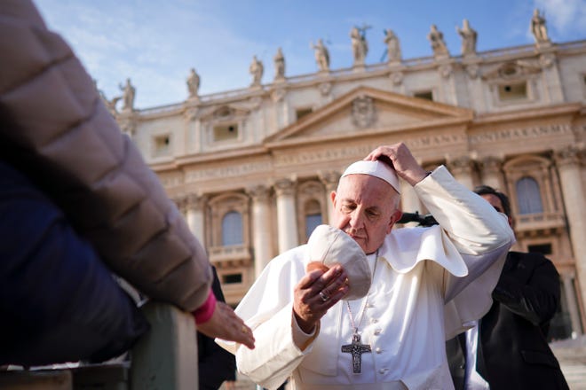 Pope Francis tries on a cap he was offered as he leaves at the end of his weekly general audience, in St. Peter's square, at the Vatican, Wednesday, Nov. 21, 2018. (AP Photo/Andrew Medichini)