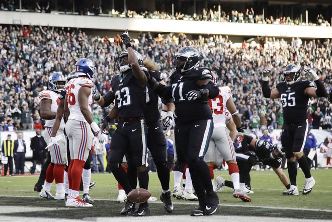 Eagles rookie running back Josh Adams (33) celebrates his 1-yard touchdown run in the fourth quarter with teammate Jason Peters (71) during Sunday's win over the Giants. [MICHAEL PEREZ/THE ASSOCIATED PRESS]