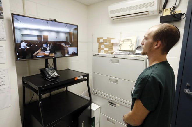 Inmate Daniel Keyes stands in front of a television in a small room inside the Bristol County House of Correction in Dartmouth during a video bail conference being held in a Fall River courtroom. (Peter Pereira/The Standard-Times)