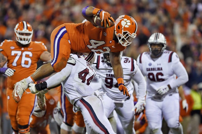Clemson's Christian Wilkins dives over South Carolina's Sherrod Greene to score a touchdown during the first half of Saturday's game in Clemson, S.C. [The Associated Press]