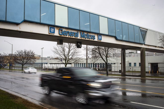 A vehicle passes under a sign at the Oshawa's General Motors plant in Ontario. General Motors will lay off thousands of factory and white-collar workers in North America and put five plants up for possible closure. General Motors is closing the Oshawa plant. [Eduardo Lima/AP Photo]