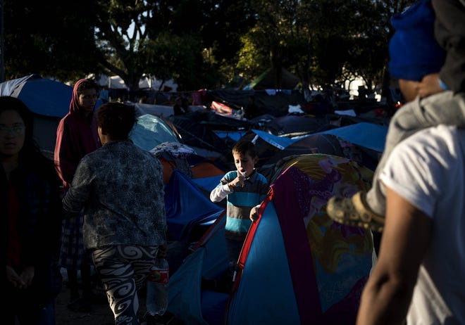 A young member of a migrant caravan brushes his teeth inside his tent at the Benito Juarez Sports Center that is serving as a shelter for migrants in Tijuana, Mexico, Monday. The mayor of Tijuana has declared a humanitarian crisis in his border city and says that he has asked the United Nations for aid to deal with thousands of Central American migrants who have arrived. [RAMON ESPINOSA/ASSOCIATED PRESS]