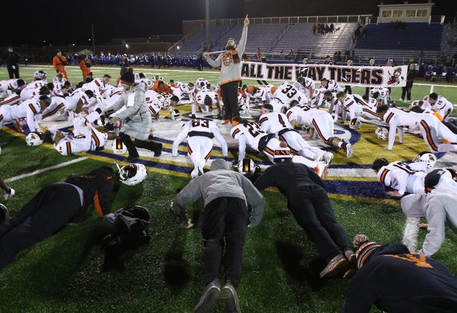 Led by defensive coach J.P. Simon, the Massillon Tigers enjoy 15 victory pushups celebrating their advancement to the 15th week of play. [Kevin Whitlock/IndeOnline.com]