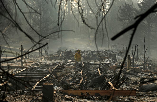 A firefighter searches for human remains in a trailer park destroyed in the Camp Fire, in Paradise, California. The massive wildfire killed dozens of people and destroyed thousands of homes. [John Locher/AP file]