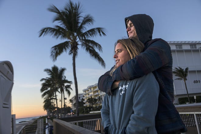Brendon Andrews and Linda Tate of West Palm Beach keep warm at sunrise in Palm Beach Wednesday, November 28, 2018. The two were watching Brendon's brother Richard surfing, and "once we get warm" were going to join him. Which they did. [LANNIS WATERS/palmbeachpost.com]