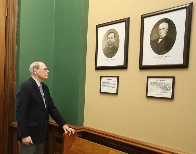 Tuscarawas County Historical Society President David Hipp looks over some of the photographs of the past judges hanging in the Tuscarawas County Courthouse. (TimesReporter.com / Jim Cummings)