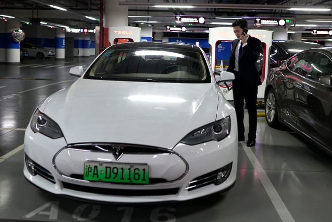 An Baojia, right, makes a phone call near his Tesla vehicle at a charging station in Shanghai. More than 200 manufacturers, including Tesla, Volkswagen, BMW, Daimler, Ford, General Motors, Nissan, Mitsubishi and U.S.-listed electric vehicle start-up NIO, transmit position information and dozens of other data points to Chinese government-backed monitoring centers, The Associated Press has found. Generally, it happens without car owners' knowledge. [AP Photo]