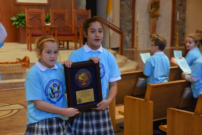 St. Jude Catholic School students Juliana Perry, left, and Natalie Oliveri hold the National Blue Ribbon plaque during the recent celebration. [CONTRIBUTED]