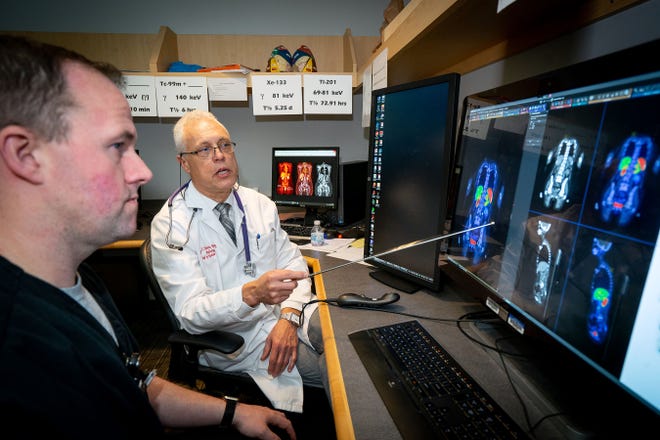Dr. Jean-Luc Urbain, chief of the section on nuclear medicine at Wake Forest Baptist Medical Center, makes a point to Jonathan Richardson, the medical center's chief nuclear medicine technologist, while reviewing images from a PET/CT scan. [WAKE FOREST BAPTIST MEDICAL CENTER PHOTO]