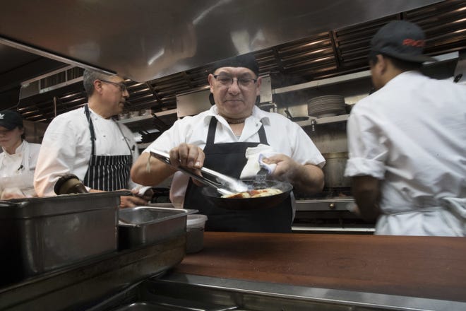 In this Tuesday, Nov. 27, 2018 photo, Chef Jacinto Guadarrama, left, prepares dishes with the help of the kitchen staff at Gotham Bar and Grill in New York. Some small businesses are making hard choices as labor and other costs keep rising. GothamþÄôs hourly wages have gone up along with the cityþÄôs minimum wage, which rose $2 an hour to $13 last December and will reach $15 this Dec. 31. The restaurant is also paying more for ingredients, especially eggs and other dairy items, key dessert components. (AP Photo/Mary Altaffer)