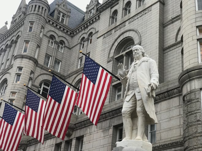A statue of Benjamin Franklin, who served as the nation’s first postmaster general, stands outside the former Post Office Building in Washington, which is now home of the Trump International Hotel. [Photo by Rick Holmes]
