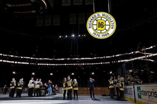 Retired Bruins player Rick Middleton, center, is flanked by family members on the rink at the TD Garden in Boston as his No. 16 is raised to the rafters Thursday night.