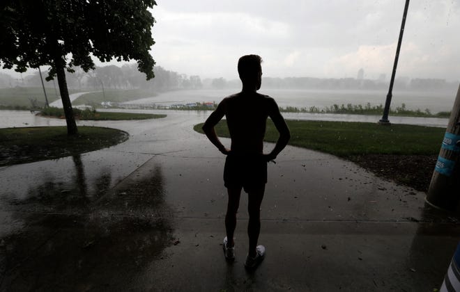In this May file photo a man takes shelter from a rainstorm while running at Gray's Lake Park in Des Moines, Iowa. Researchers have found dozens of unconscious biases that can drive people to make money decisions they later regret. These behavioral economics concepts include things like “anchoring”, when a specific and perhaps arbitrary number you have in mind sways your decision-making. Or, the “endowment effect” can cause you to overvalue something simply because you own it, leading you to cling to a stock that’s tanking. [Associated Press/Charlie Neibergall]