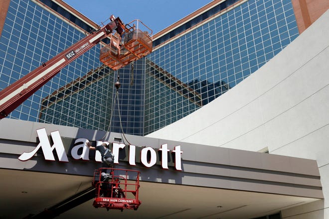 In this Tuesday, April 30, 2013, file photo, a man works on a new Marriott sign in front of the former Peabody Hotel in Little Rock, Ark. Marriott says the information of up to 500 million guests at its Starwood hotels has been compromised. It said Friday, Nov. 30, 2018, that there was a breach of its database in September, but also found out through an investigation that there has been unauthorized access to the Starwood network since 2014.